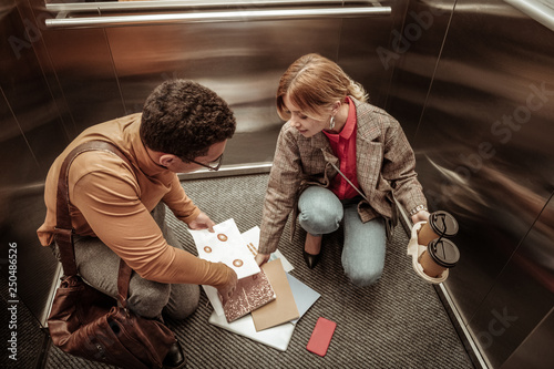 Inattentive woman dropping documents on the floor in elevator photo