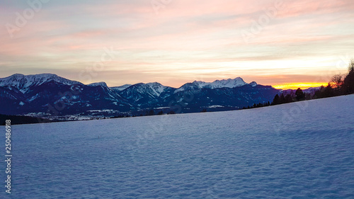 Snowy Sunset in Ludmansdorf, Kathreinkogel, Schiefling am See. Sky is pink and yellow. Sun hides behind Alps. Landscape is not spoiled by human. Romantic escape. Pastel sky. Perfect powder snow.