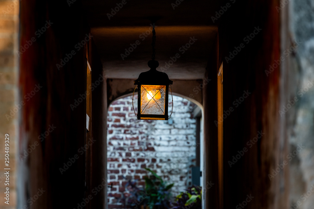 Naklejka premium Nobody in old vintage stone brick architecture and narrow dark alley with illuminated silhouette lantern passage tunnel