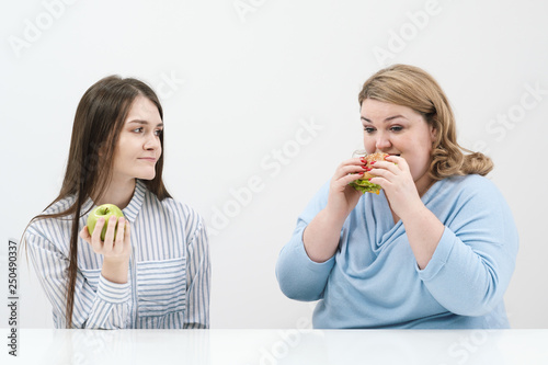 Slender girl eats healthy food  Fat woman eats harmful fast food. On a white background  the theme of diet and proper nutrition.