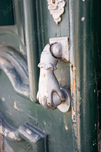 Beja, Alentejo, Portugal. Detail of a wooden door. Each gate knocker has the shape of a hand