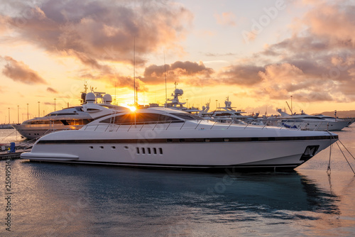 Beautiful orange sunset in the sea harbor with moored yachts. Expensive 92 foot yacht at the pier during sunset © Dmitrii Potashkin