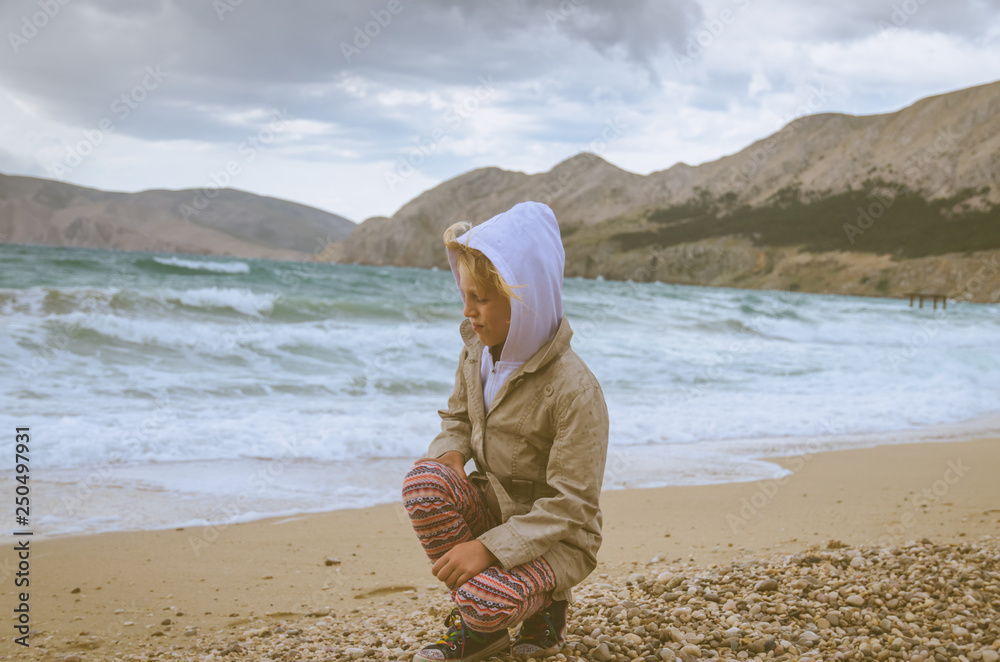 child on the pebble beach in windy weather