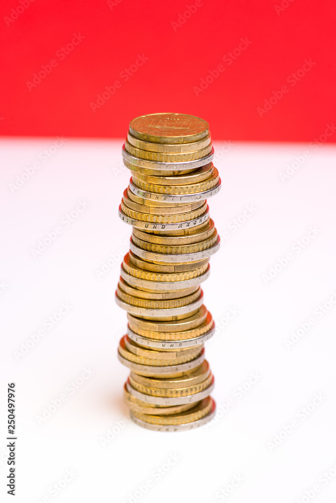 Coins stacked on each other in different positions on a red and white background Coins stacked on each other in different positions on a red and white background