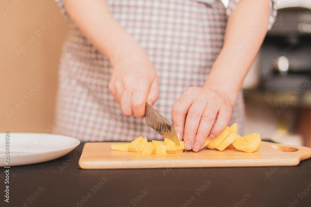housekeeper cuts potatoes on a wooden board