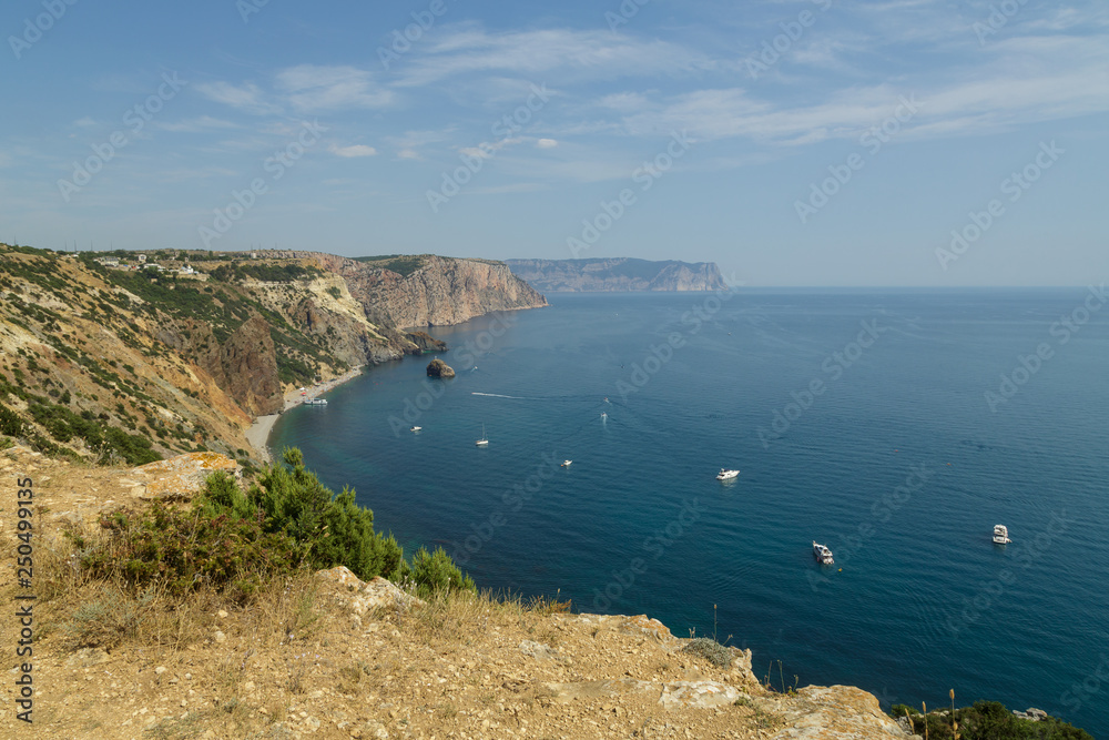 Rocks overgrown with rare green vegetation and a view of the sea.