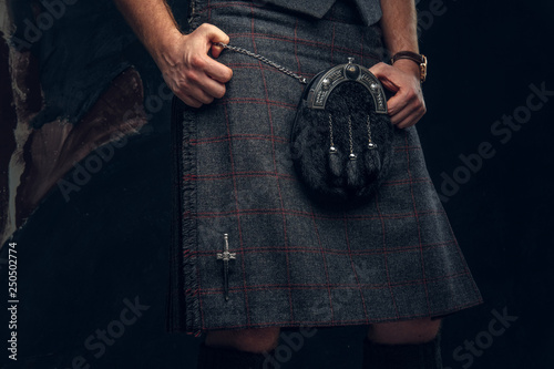 Traditional Scottish costume. Kilt and sporran. Studio photo against a dark textured wall