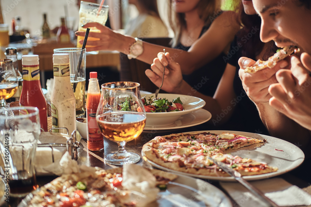 Pizza time. Young friends students eat pizza and salads in an outdoor caf during lunch break 