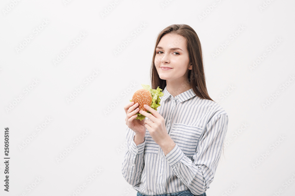 Young beautiful brunette girl on a white background with a hamburger in her hands. Young beautiful brunette girl on a white background with a hamburger in her hands.