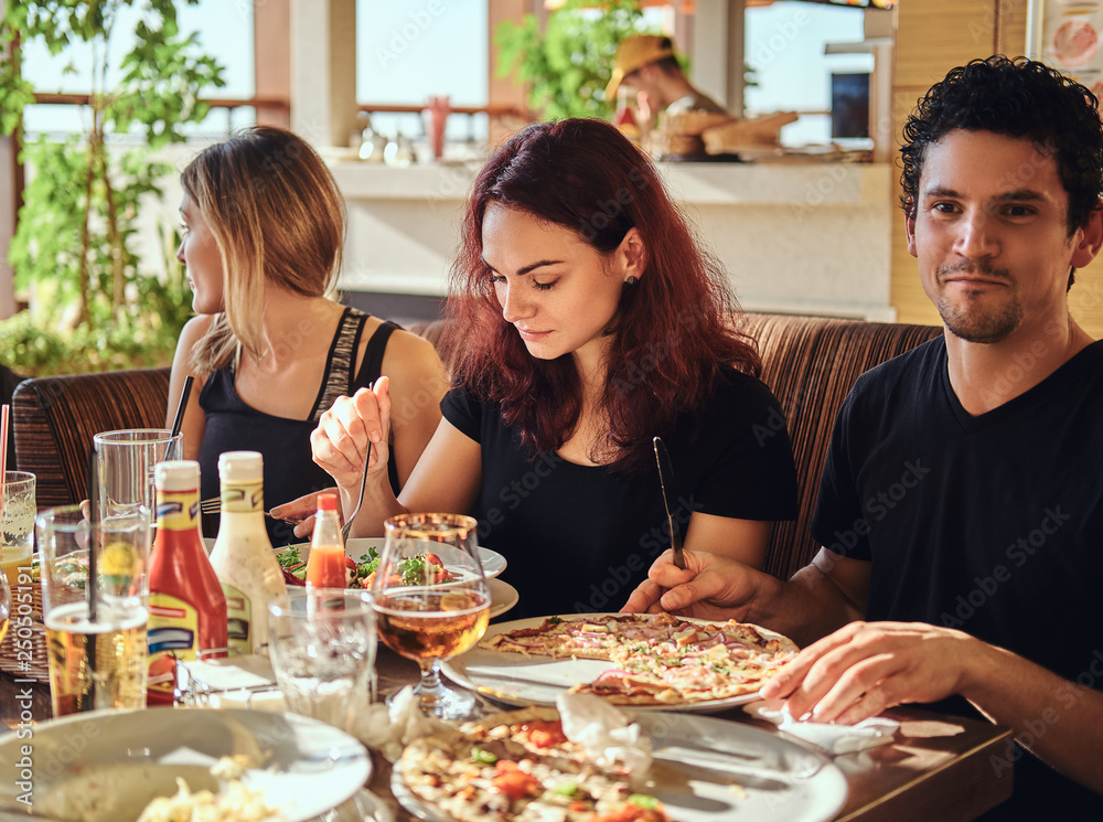 Food and people concept. Cheerful young friends enjoying food and having fun together in the restaurant or cafe outdoor Food and people concept. Cheerful young friends enjoying food and having fun together in the restaurant or cafe outdoor
