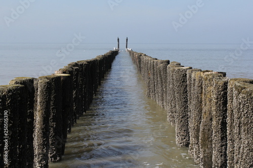 two rows of beach poles in the sea with high tide