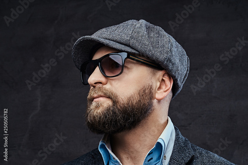 Close-up portrait of a successful stylish man in sunglasses wearing a beret and jacket photo