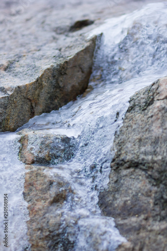 Icicles on granite rocks. Frozen water on stones. Clear water in winter. Freshwater source in mountains