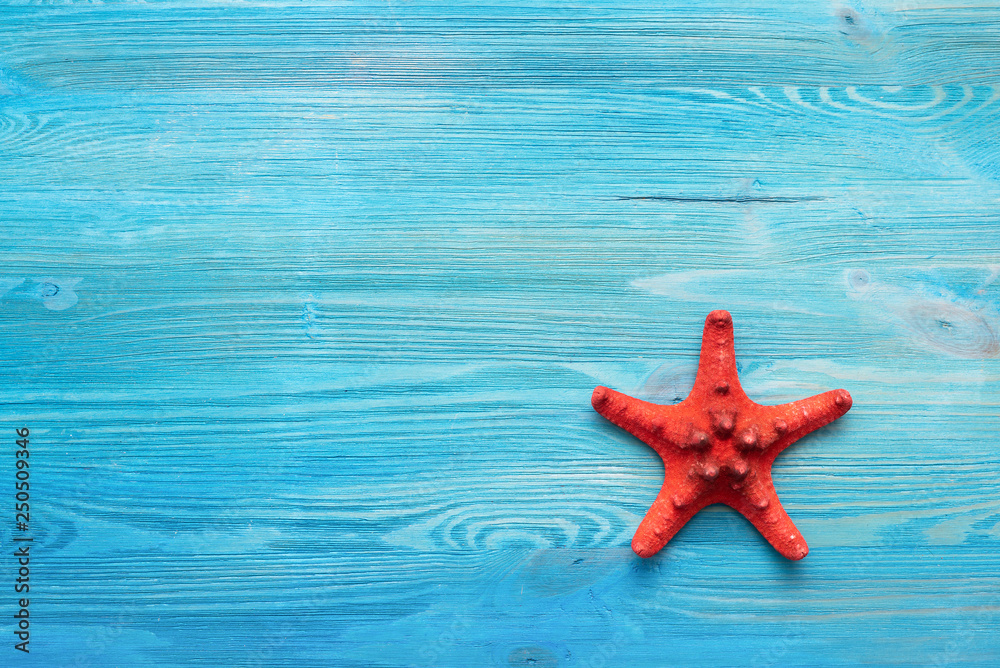 Summer sea vacation concept background with copy space. Red starfish on a blue wooden floor background. Summer sea vacation concept background with copy space. Red starfish on a blue wooden floor background.