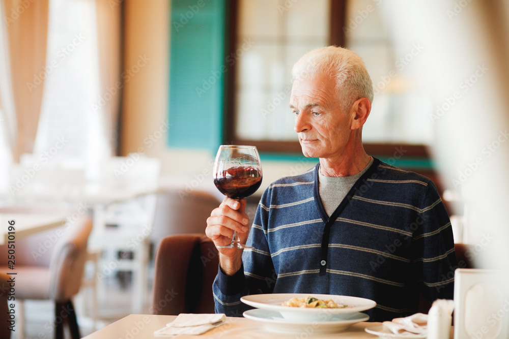 Old man sits at the restaurant, tasting wine and paste Old man sits at the restaurant, tasting wine and paste