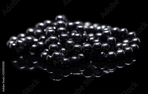 Natural black pearl beads on a black background with reflection