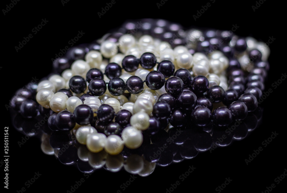 Two mixed strands of natural black pearl beads on a black background with reflection Two mixed strands of natural black pearl beads on a black background with reflection