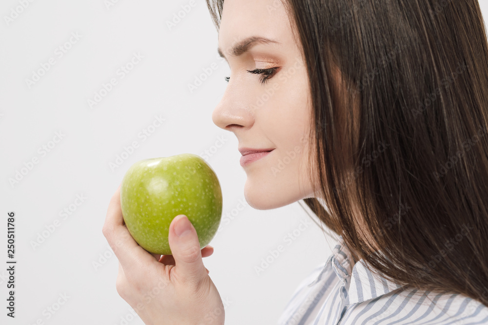 Young beautiful brunette girl on a white background holding a fresh green apple. Young beautiful brunette girl on a white background holding a fresh green apple.