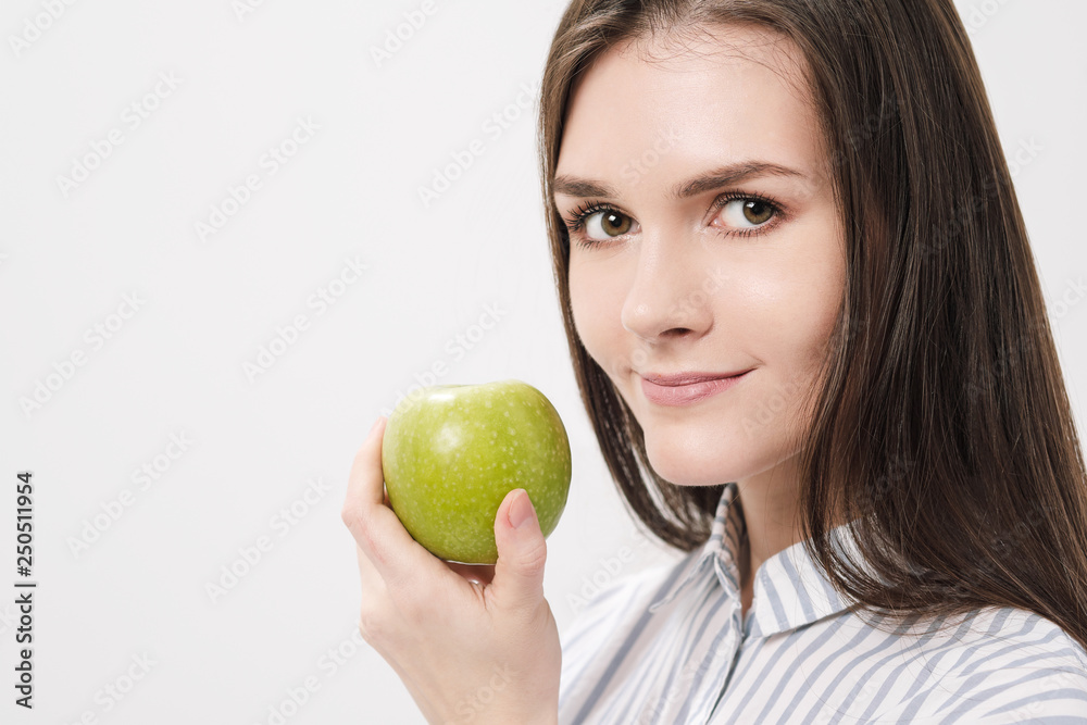 Young beautiful brunette girl on a white background holding a fresh green apple. Young beautiful brunette girl on a white background holding a fresh green apple.