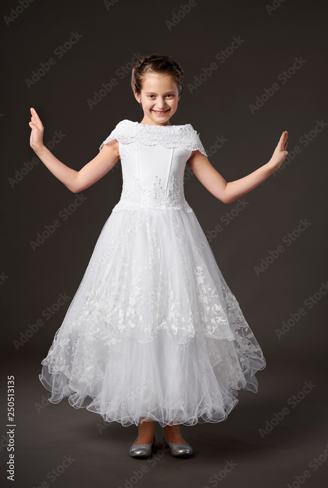 little girl is dressed in a white ball gown, dark background