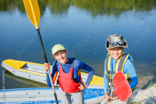 Two kids enjoying kayak ride on beautiful river. Little boy and teenager girl kayaking on hot summer day. Water sport fun.