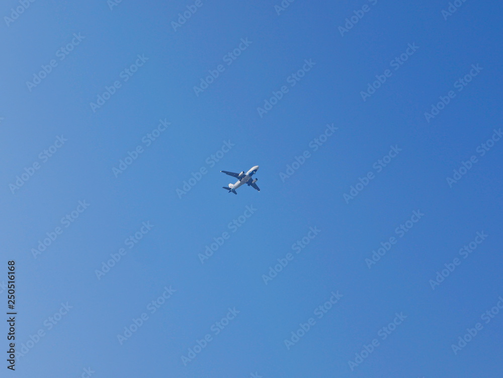 An airplane flying across blue sky, from a far distance, in a sunny day in summer time An airplane flying across blue sky, from a far distance, in a sunny day in summer time