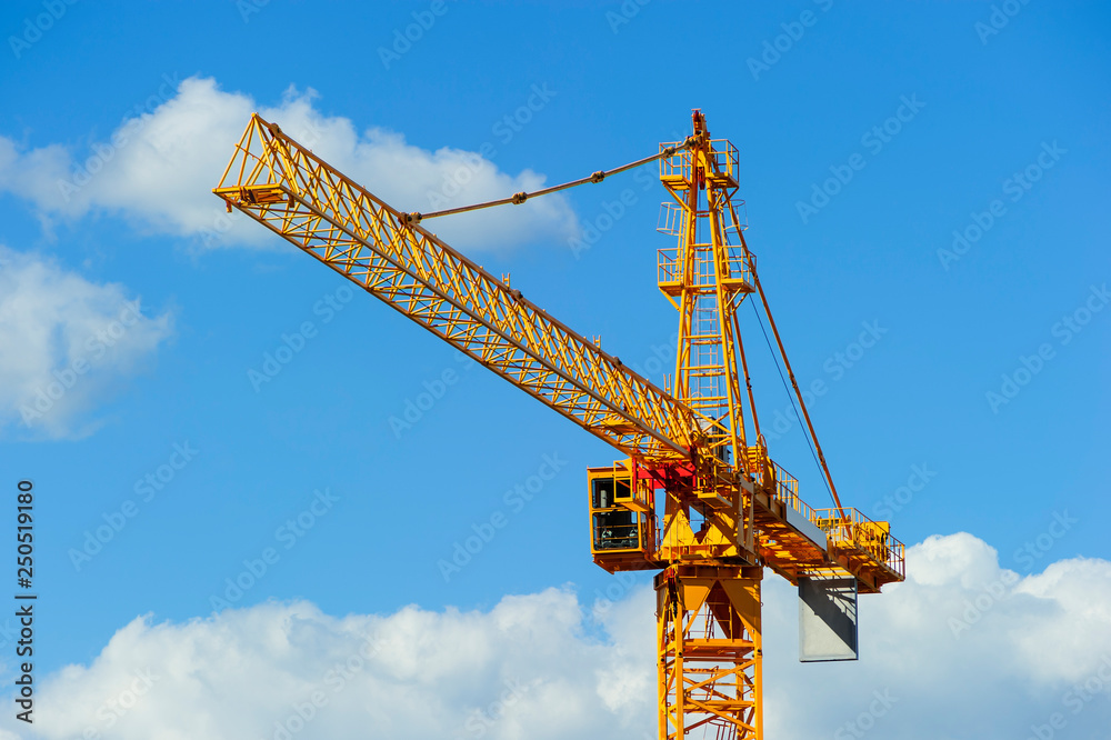 Yellow construction tower crane, heavy industry, blue sky and white clouds on background Yellow construction tower crane, heavy industry, blue sky and white clouds on background