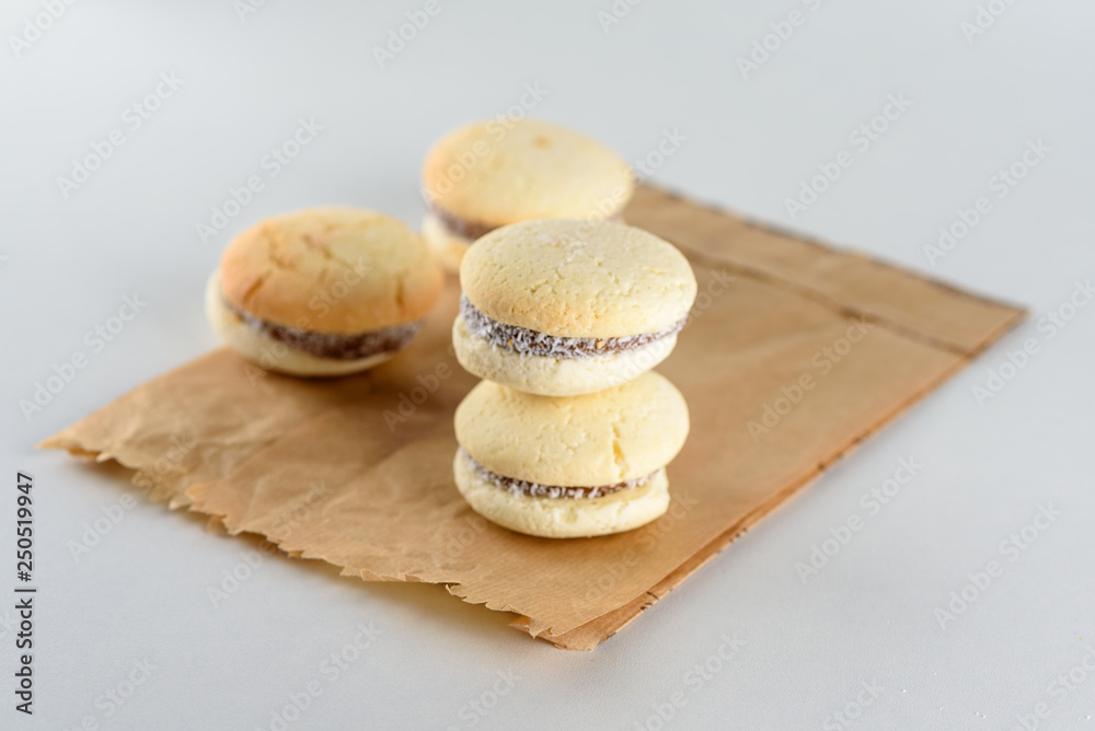 Delicious Argentinian cookies alfajores with cream dulce de leche close-up on the plate. White vanilla macaroons on white background. French delicate dessert for Breakfast in the morning light.