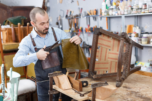 Craftsman reupholstering chair in workshop photo