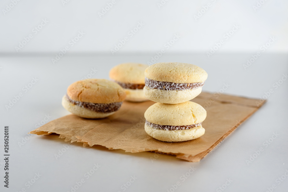 Delicious Argentinian cookies alfajores with cream dulce de leche close-up on the plate. White vanilla macaroons on white background. French delicate dessert for Breakfast in the morning light. Delicious Argentinian cookies alfajores with cream dulce de leche close-up on the plate. White vanilla macaroons on white background. French delicate dessert for Breakfast in the morning light.