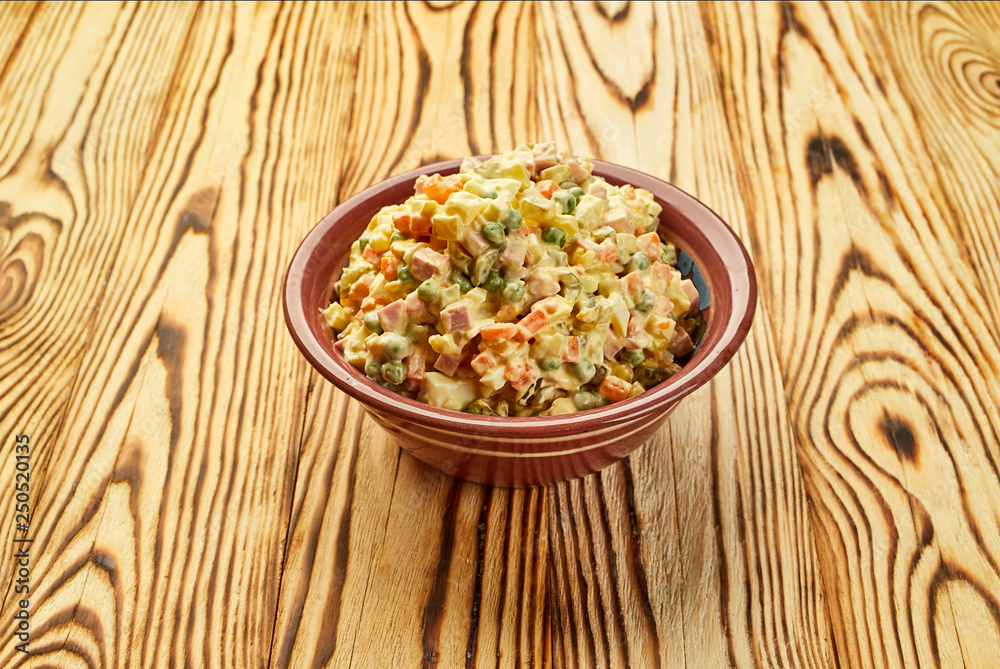 Russian traditional Christmas and New year salad Olivier with vegetables and meat on a plate with wooden background Russian traditional Christmas and New year salad Olivier with vegetables and meat on a plate with wooden background