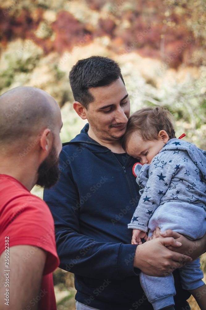 A man talking to another man who holds the child A man talking to another man who holds the child
