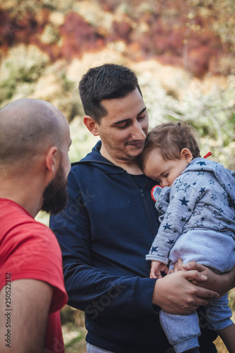 A man talking to another man who holds the child