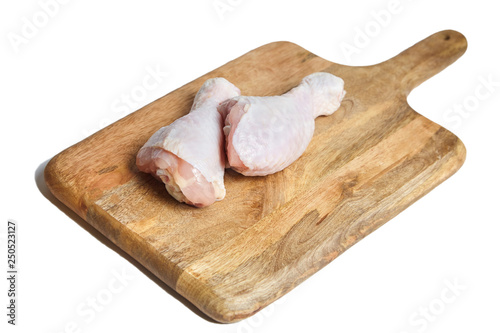 Chicken legs with skin lying on a wooden cutting board. Poultry meat isolated on white background