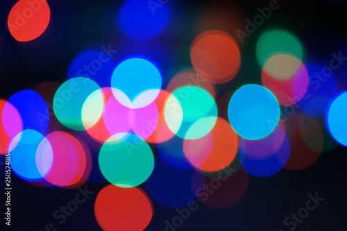 Multi-color blue holiday garland. Garland is blurred. Many big colorful round lights. Fully defocused photo. Blurred background and foreground. Holiday mood. New Year and Christmas is coming.