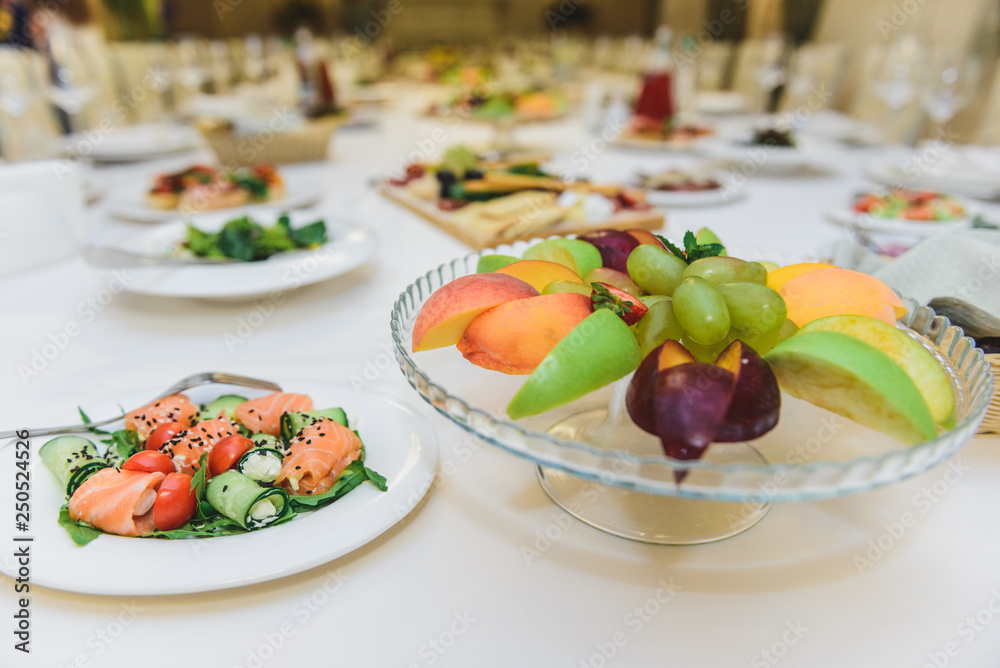 table with food covered with a white tablecloth. Fruits in the foreground.