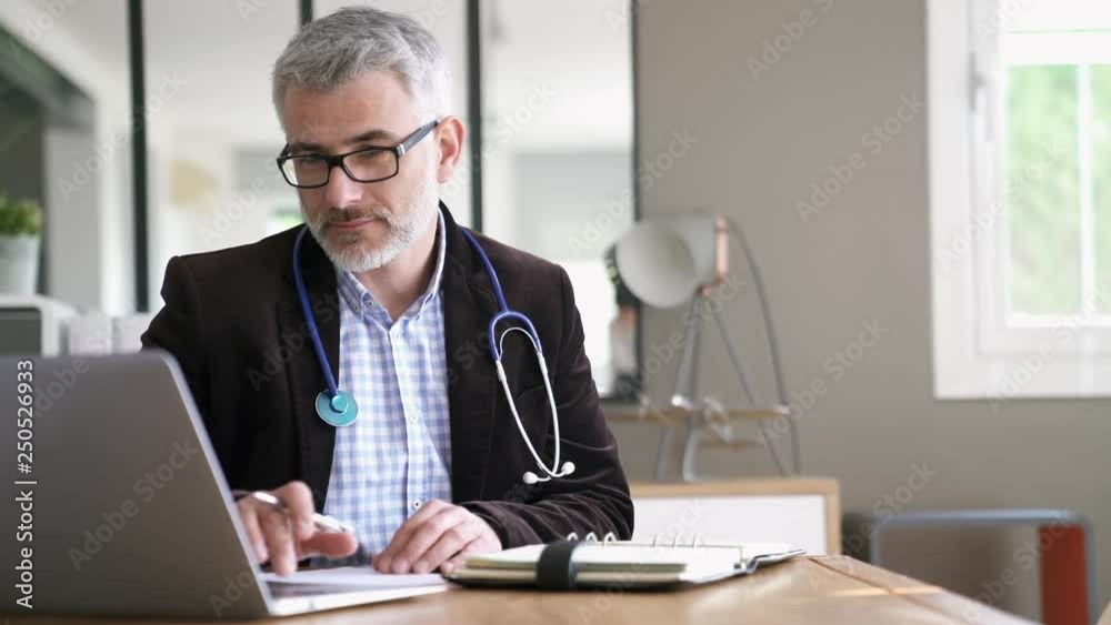 General practitioner sitting at his desk in medical office