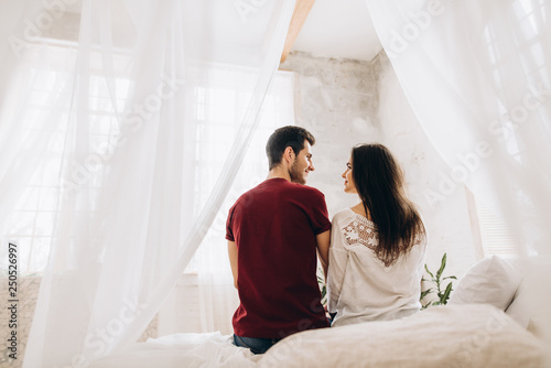 Obraz na plátně Happy couple spending time together on the bed in their cozy apartment