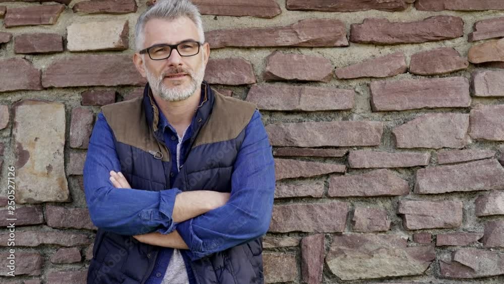 Man standing and leaning on stone wall Man standing and leaning on stone wall