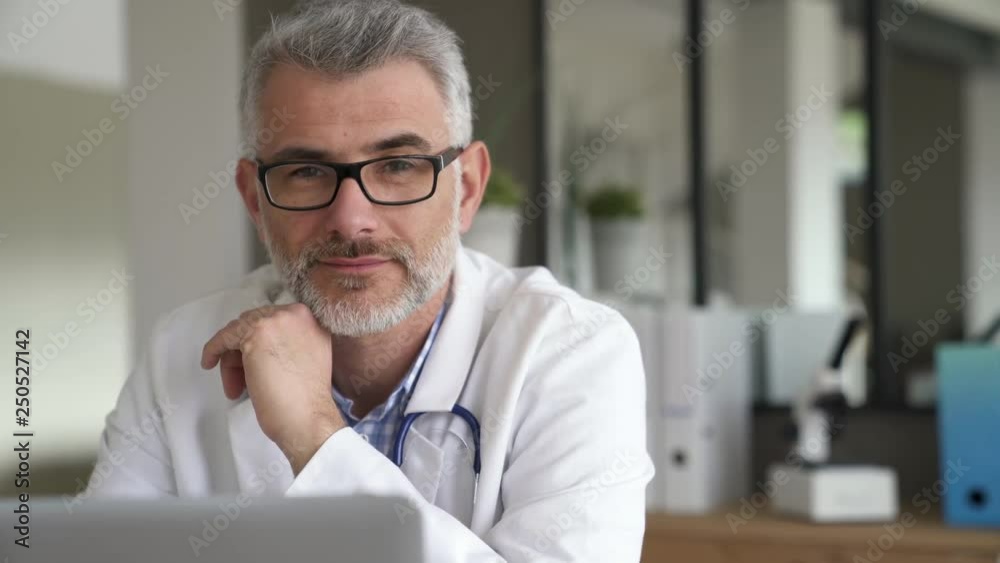 Mature doctor in office working on laptop computer Mature doctor in office working on laptop computer