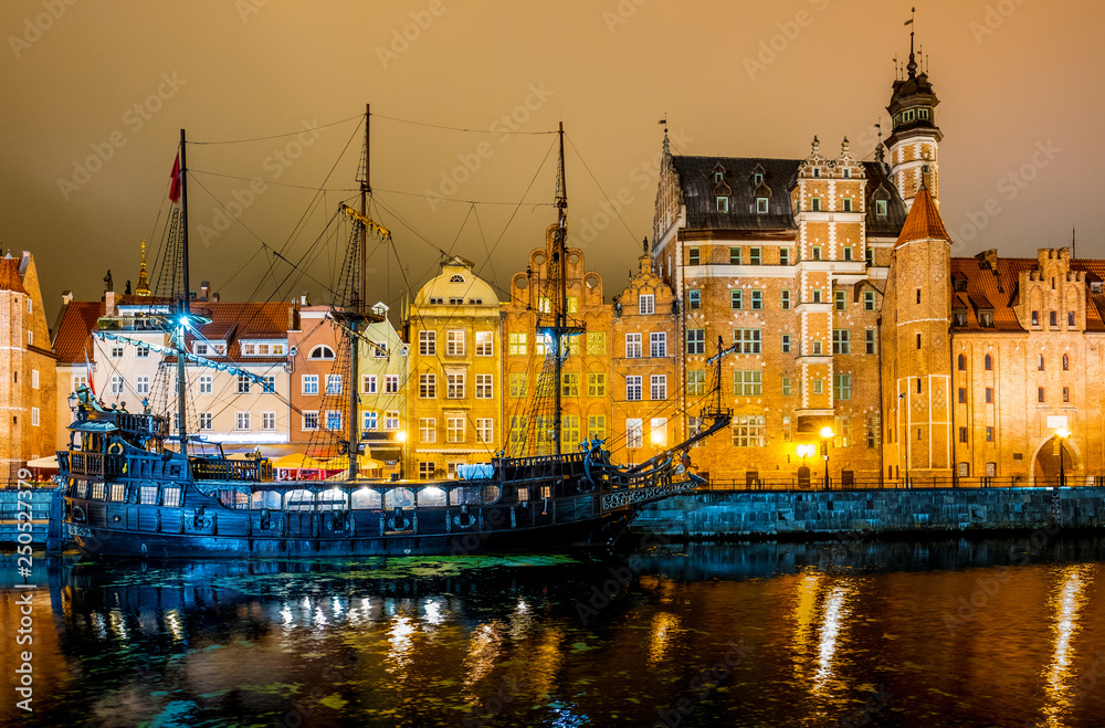 The dark view of Gdansk, old town and famous crane at amaizing night with light reflections with wooden sailingboat moored on pier. Poland