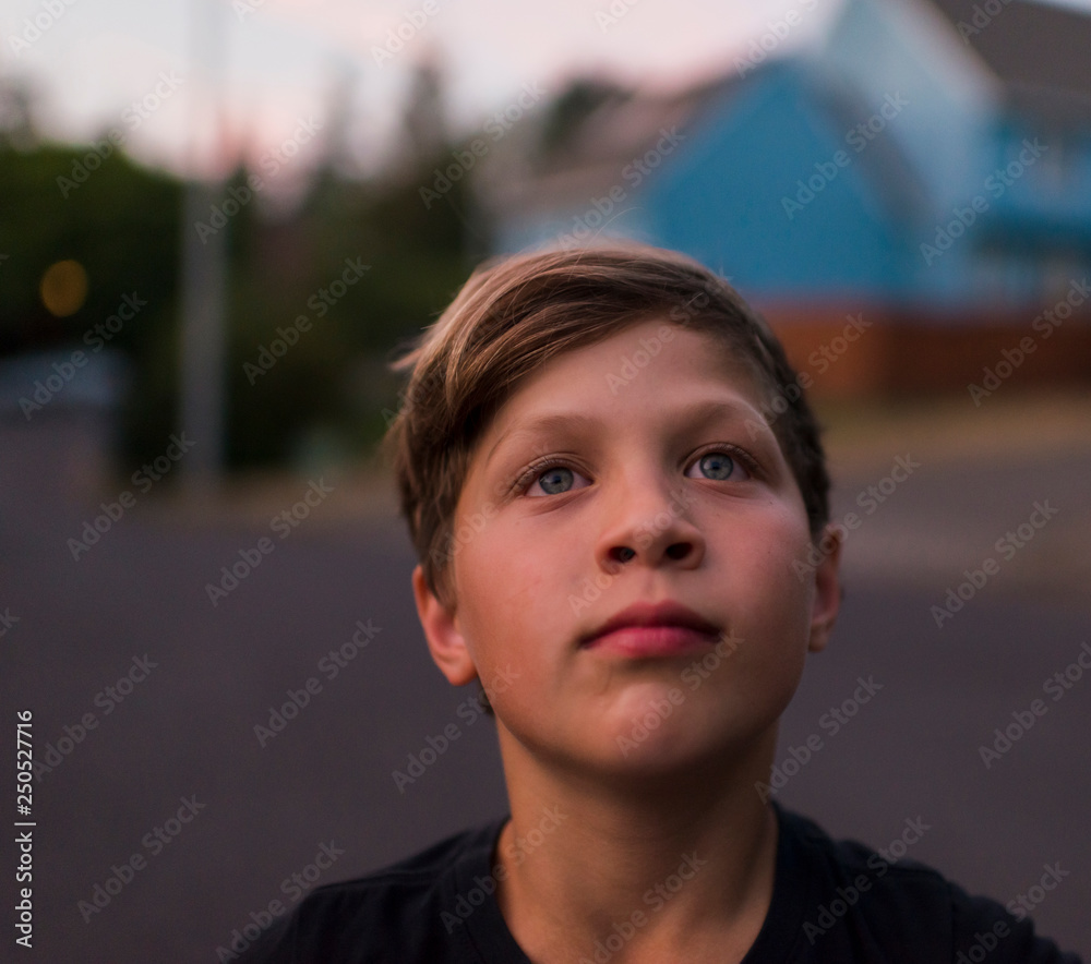 Close up of thoughtful boy standing on road during sunset Close up of thoughtful boy standing on road during sunset