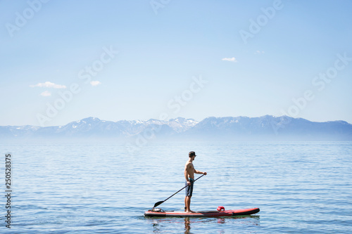 Side view of shirtless man paddleboarding in lake