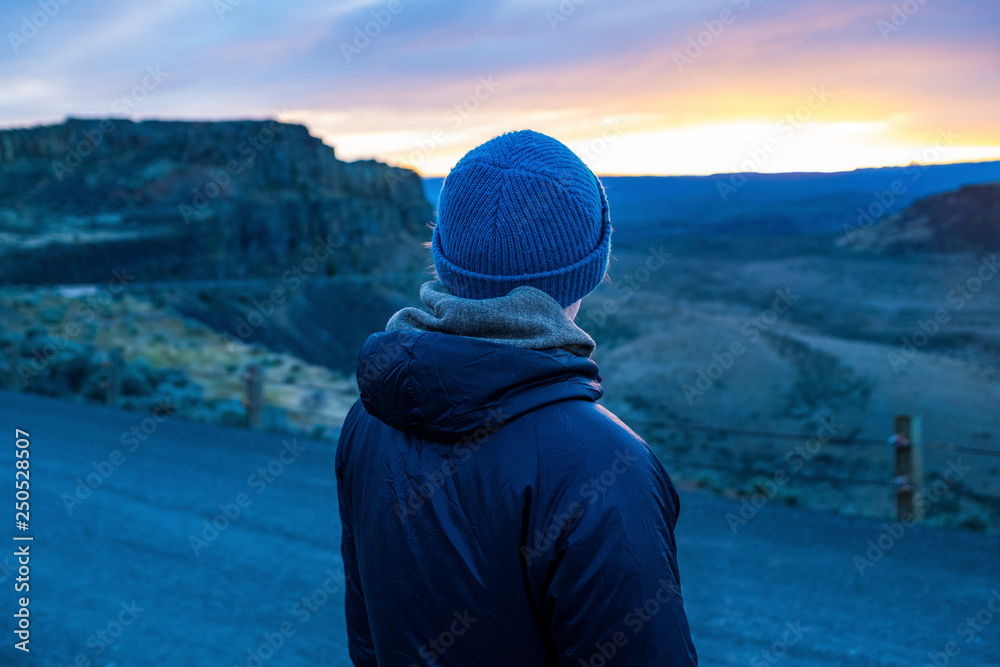 Rear view of woman wearing warm clothing looking at landscape during sunset Rear view of woman wearing warm clothing looking at landscape during sunset