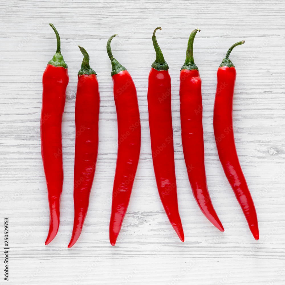 Hot red chili peppers on a white wooden background. From above, overhead, top view. Closeup. Hot red chili peppers on a white wooden background. From above, overhead, top view. Closeup.