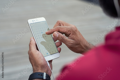 Cropped image of man looking calendar in smart phone while standing outdoors photo