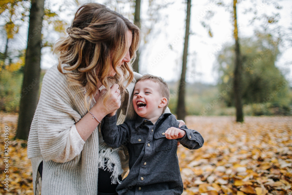 Cheerful mother and son playing in forest during autumn Cheerful mother and son playing in forest during autumn