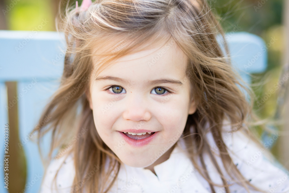 Close-up portrait of cute smiling girl sitting on swing in yard