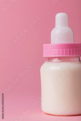 Baby bottle full of milk on a pink background