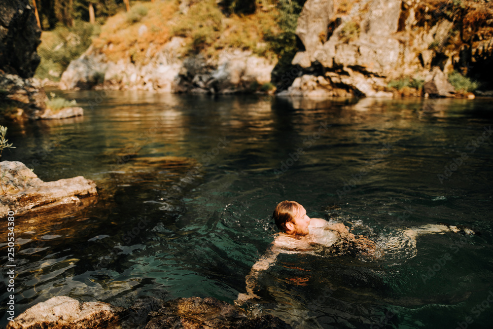 High angle view of shirtless man swimming in river at forest High angle view of shirtless man swimming in river at forest